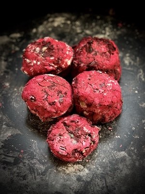 Close up of beetroot cutlets on a black background. Flour dusted around them. A link to Chef Susmitha Veganosaurus' recipe blog.