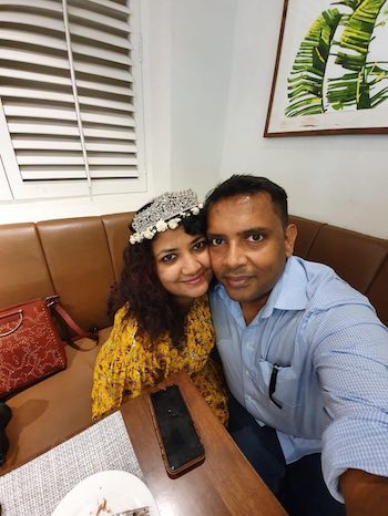 Happy Indian couple pressing their cheeks together and smiling at the camera.