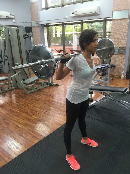 Super thin woman, standing and lifting huge weights with power and confidence, in a gym