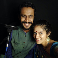Indian couple, man and woman. Wearing traditional clothes and smiling at the camera, black background. Dr. Achyuthan Eshwar and Shyamala Suresh.