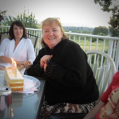 Photo of Karen Warwick before her healthy weight loss journey began. Heavyset woman seated at a chair with friends, large cake in front of her. Smiling at the camera.