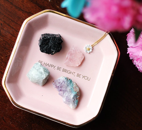 Four crystals on a pink square plate/ Text: Be Happy, Be Bright, Be You. Spirituality. Coaching.