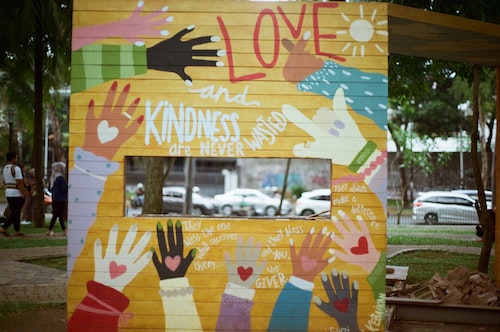 Graffiti on wall. Hands of many people. Messages of love, kindness and giving.