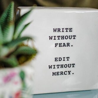 Ceramic square with the text "write without fear. edit without mercy." On the left, blurred succulent plant in a small pot closer to the camera. Kill Your Darlings.