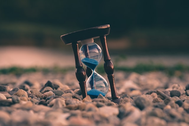 Hourglass with the sand halfway through. Placed tilted on small stones.