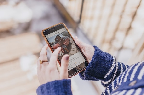 Close up of woman's hand holding her phone, lost in the world of Instagram and reels