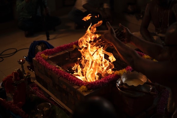 Close up of religious yagna/homa ritual fire. Hands putting offerings into the fire.
