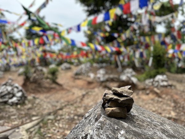 Close up of small stones stacked on top of each other, colourful Buddhist flags in the background. Location: Flag Point, Dharamkot (near Dharamshala) Himachal Pradesh