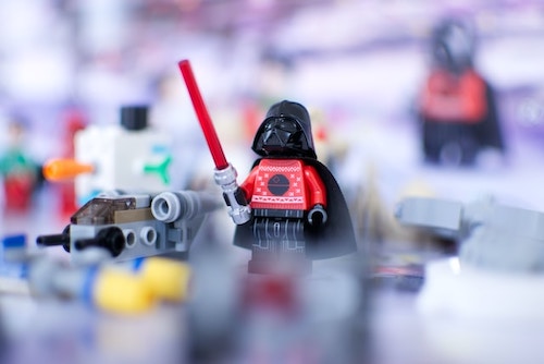 Playfulness. Mini Darth Vader Lego figurine. Wearing his tiny helmet and holding a wee red light saber.