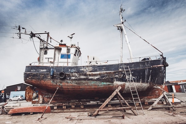 Old broken down wooden ship in yard with ladders around it