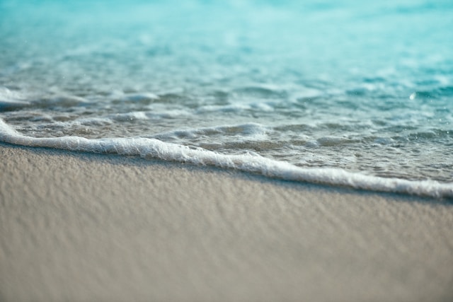 Close up of white sandy beach with turquoise blue water.