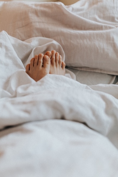 Blanket covered feet in bed. Ready and comfortable to do a sleep meditation and fall into a healing asleep.