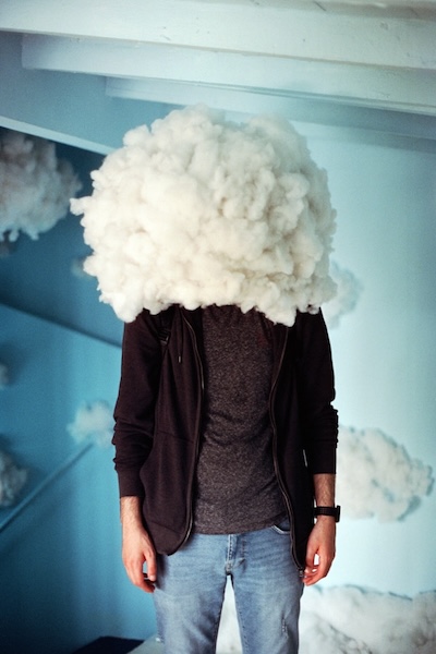 Man standing with a big cloud of fluff covering his head and face.