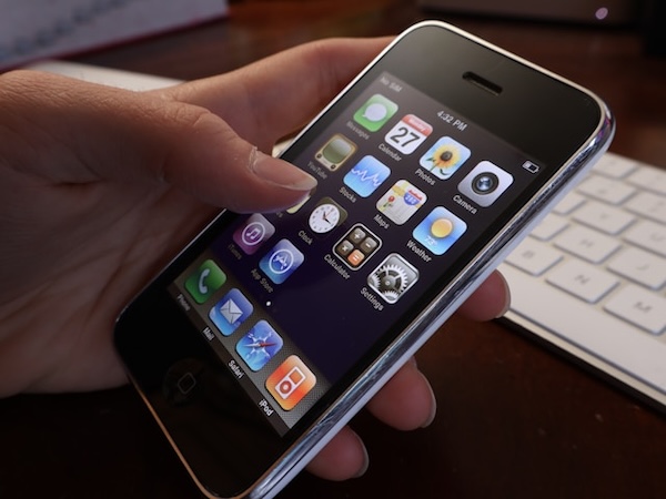 Hand holding a vintage iPhone. Using the phone to remind you helps reduce your mental burden.