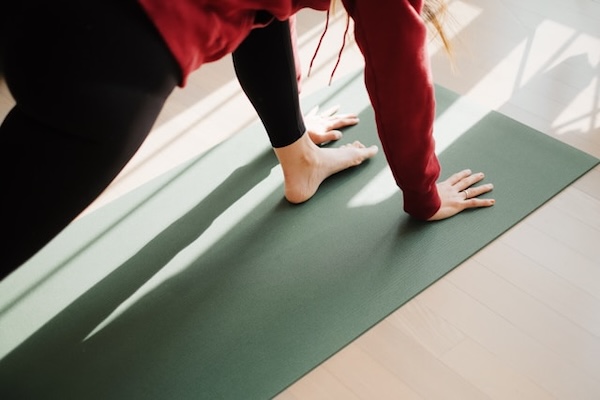 Hands and foot of person doing a gentle yoga stretch on mat.