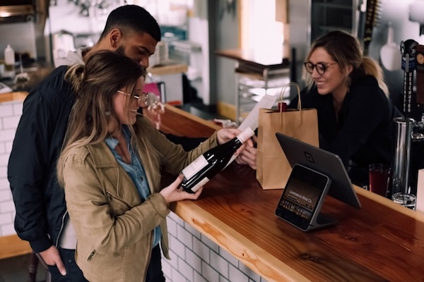 People laughing together and paying for something over a cash counter.